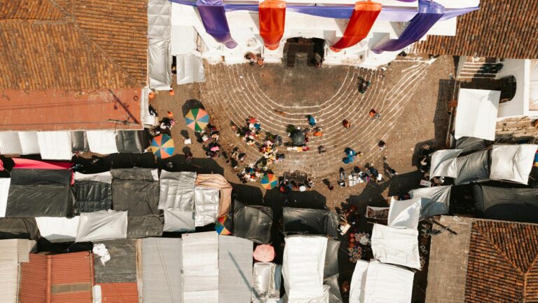 Aerial view of a bustling festival plaza with colorful tents and umbrellas.